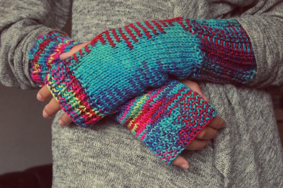 A cozy pair of hand-knitted fingerless gloves worn by someone holding a warm mug