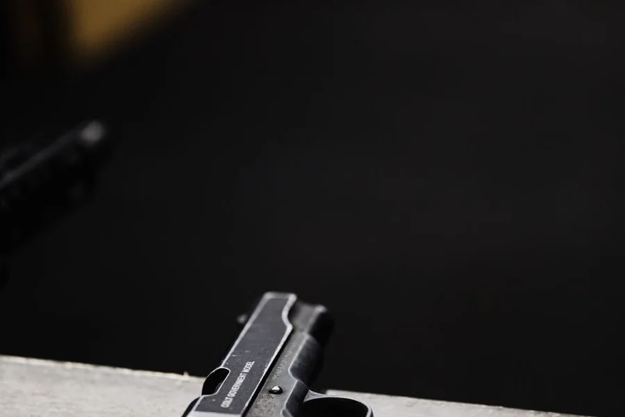 close up of pistol slide hammer and checkered grip on wooden display stand