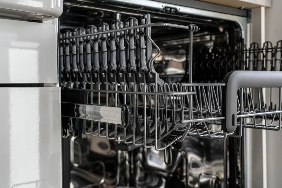 Clean plates and glassware stacked inside stainless steel dishwasher rack